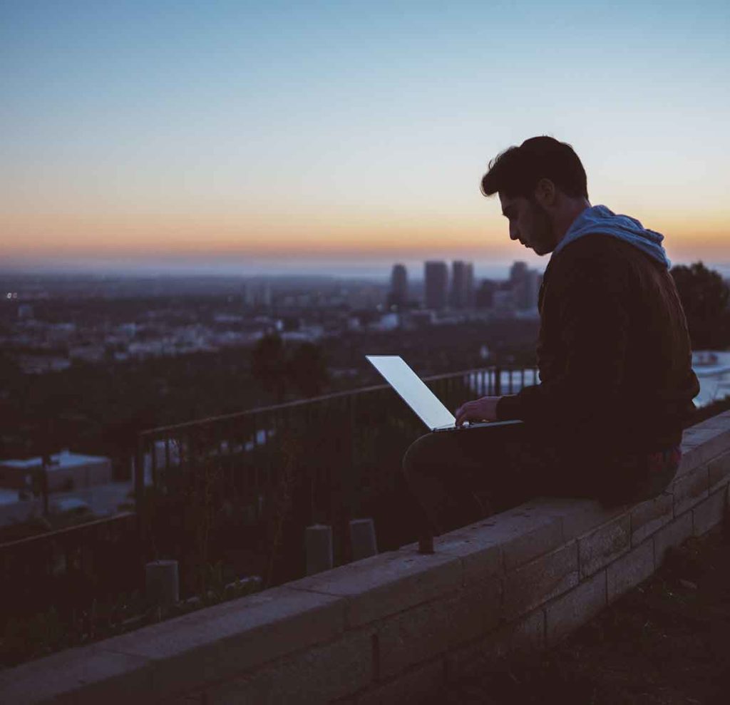 man on rooftop using laptop